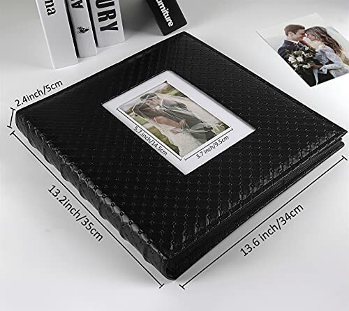 Black photo album with smartphone on wooden table.