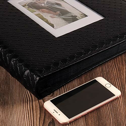 Black photo album with smartphone on wooden table.